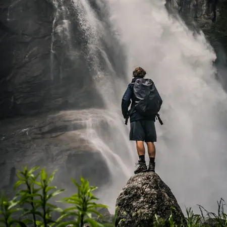 Person steht auf einem Felsen vor dem Krimmler Wasserfall.