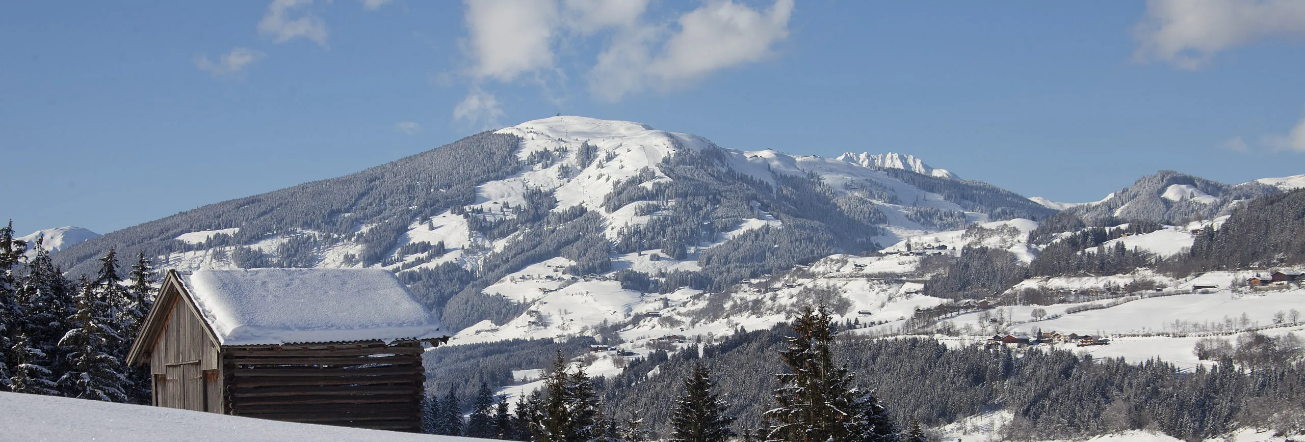 Winterlandschaft mit schneebedeckten Bergen und einem Holzhaus