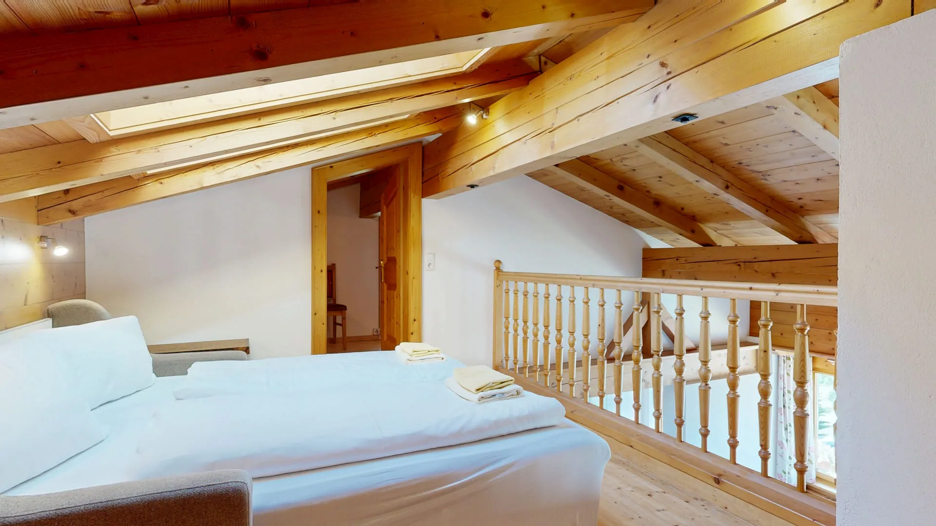 Helles Chalet mit Holzbalkendecke, freundlichem Schlafzimmer und Treppe.