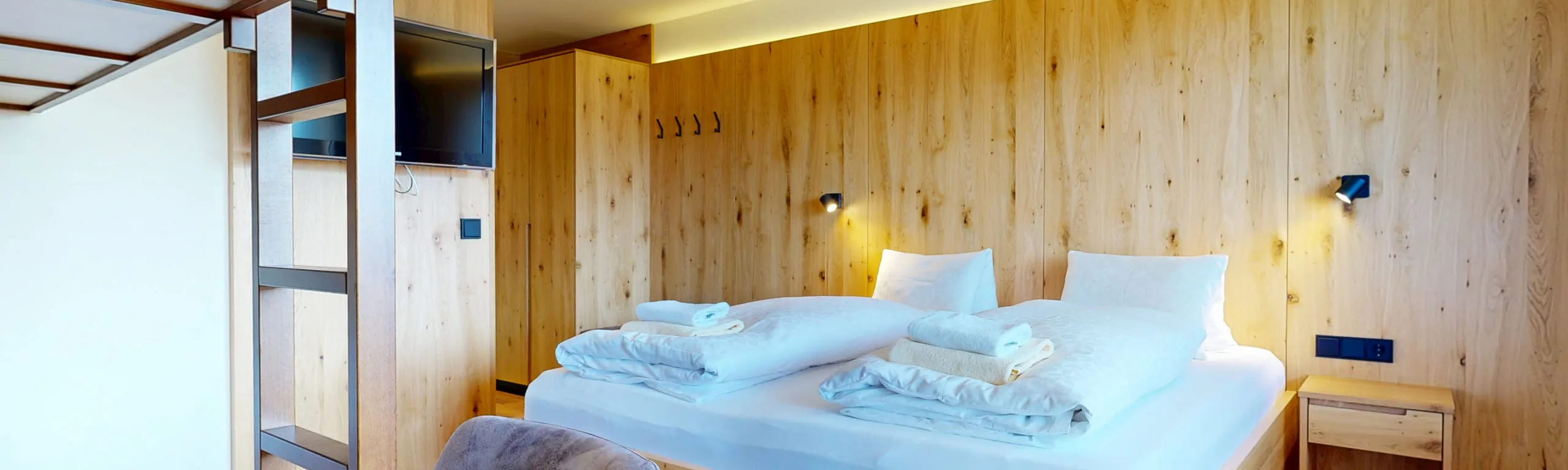 Überblick auf ein modernes Schlafzimmer mit Holzwänden und Bettwäsche