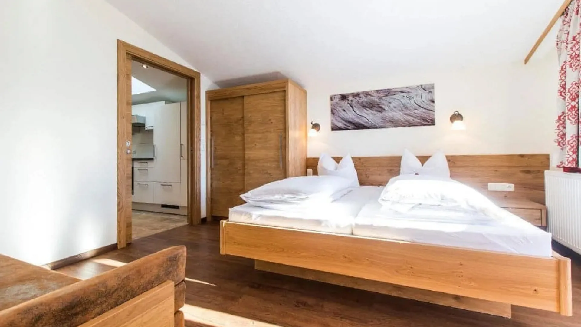 Helles Zimmer mit Holzbetten, Möbeln und angrenzender Küche