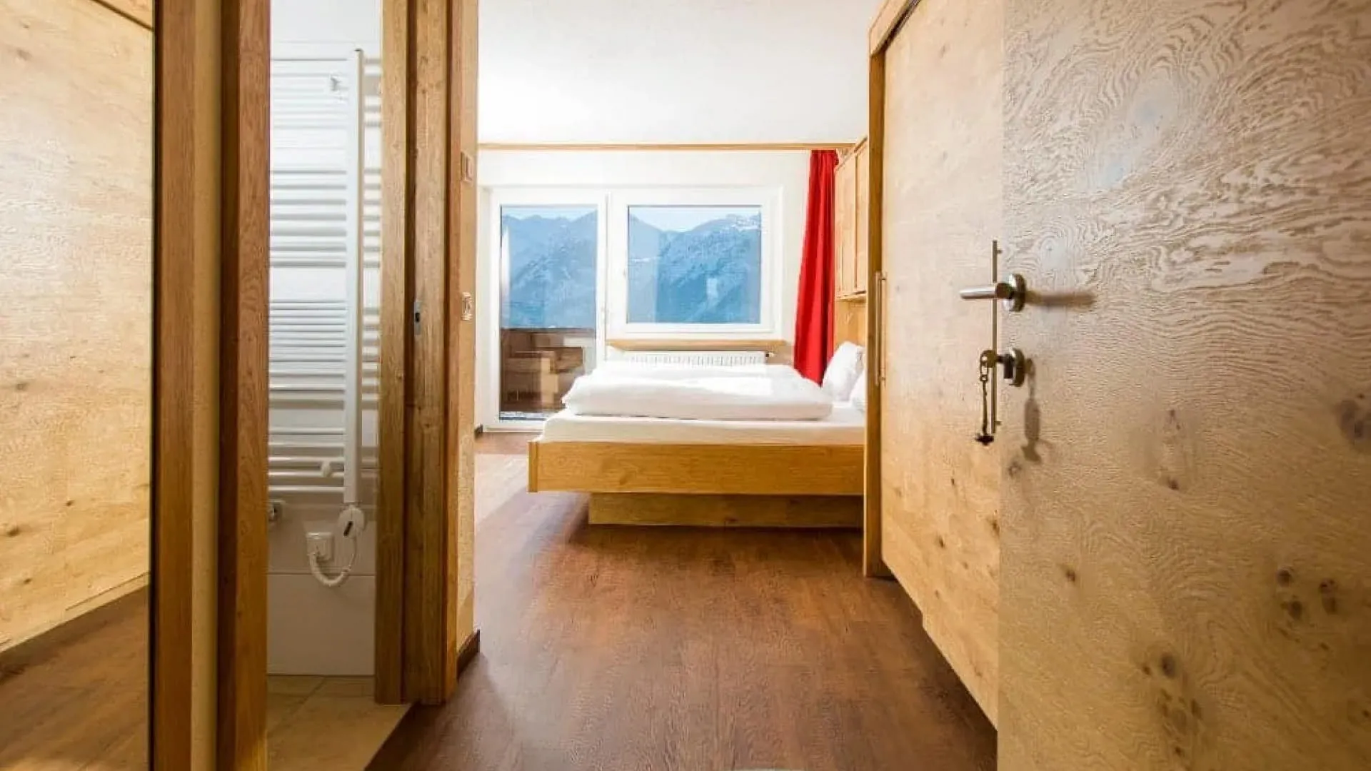 Heller Innenraum mit Holzverkleidung und Blick auf die Berge durch ein Fenster.