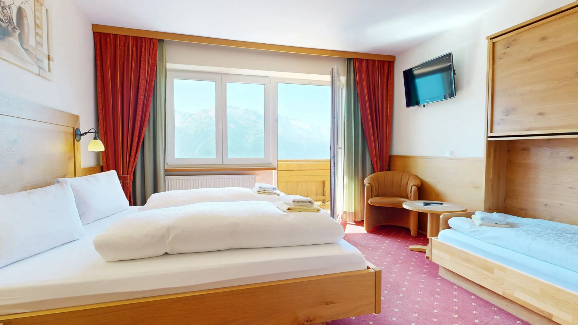Zimmer mit zwei Betten, Balkon und Fernseher, Aussicht auf die Berge.