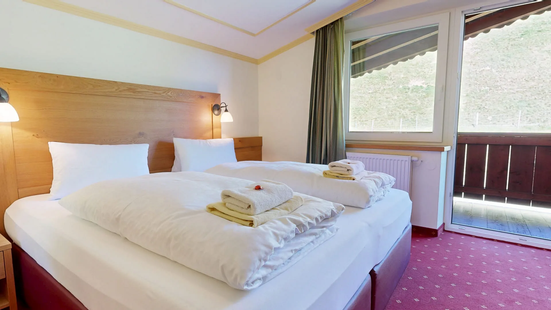 Helles Schlafzimmer mit einem Doppelbett und Blick auf die Hohe Tauern