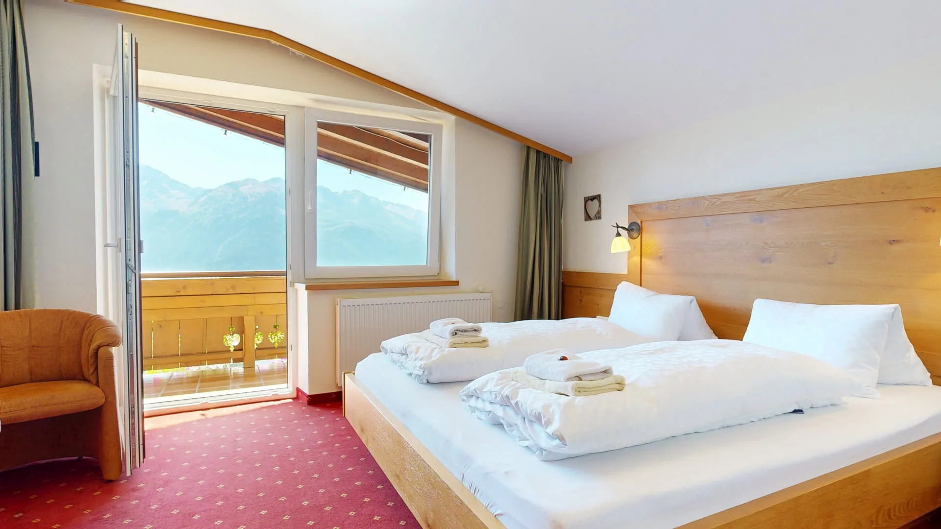 Helles Schlafzimmer mit Balkon und Blick auf die Hohe Tauern, Holzmobiliar vorhanden.