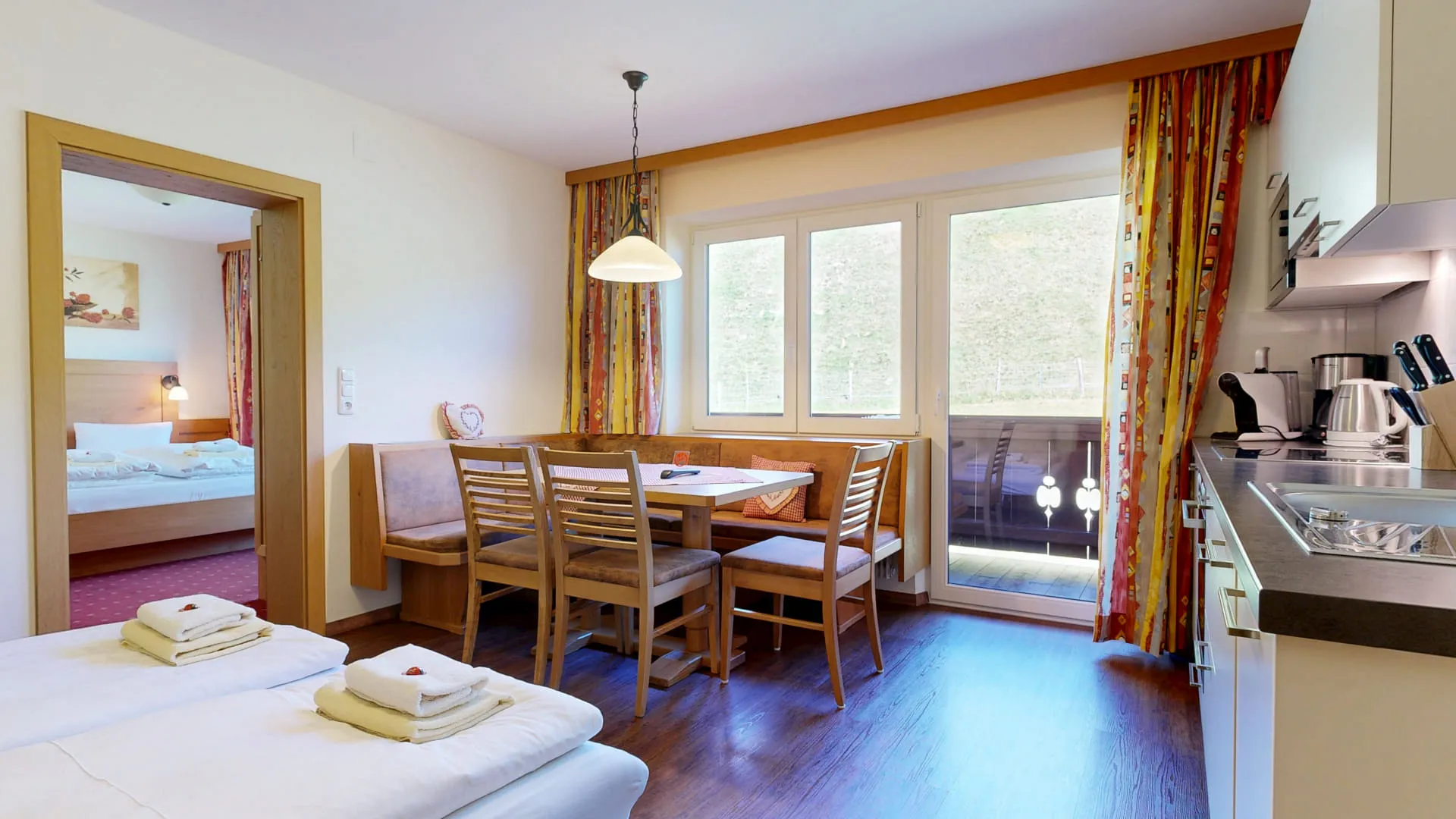 Helles Wohnzimmer mit Esstisch, Stühlen und Blick auf den Balkon.