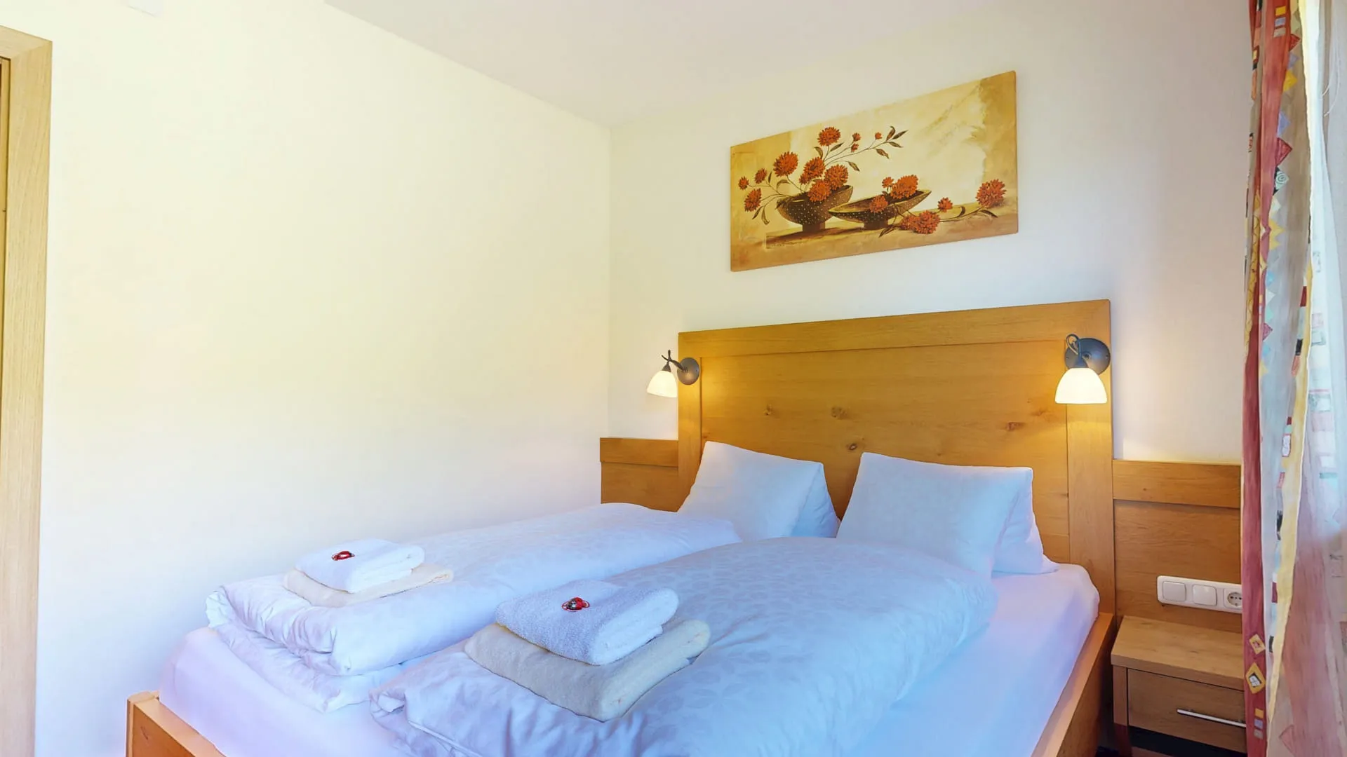 Zimmer mit Doppelbett, Kunstwerk an der Wand und Nachttischlampen