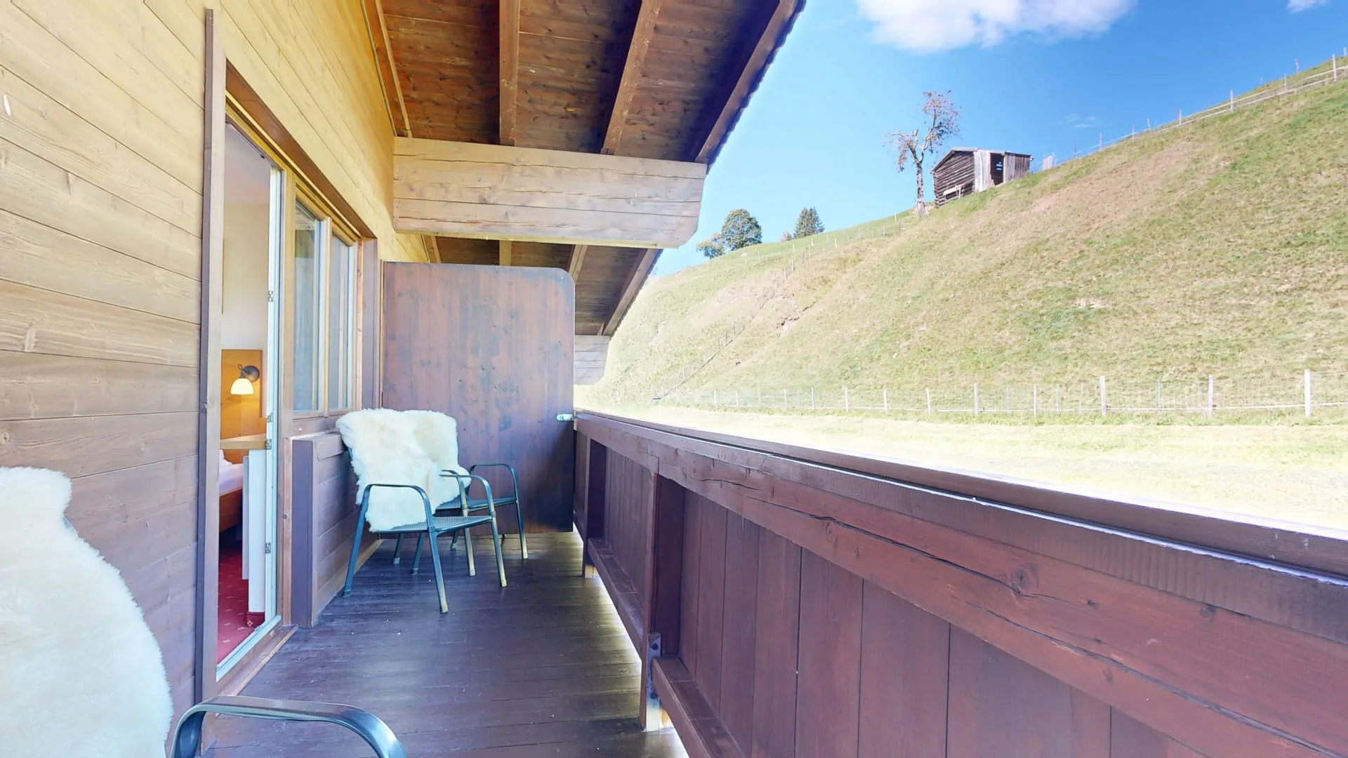 Balkon mit Blick auf eine grüne Wiese und blauen Himmel