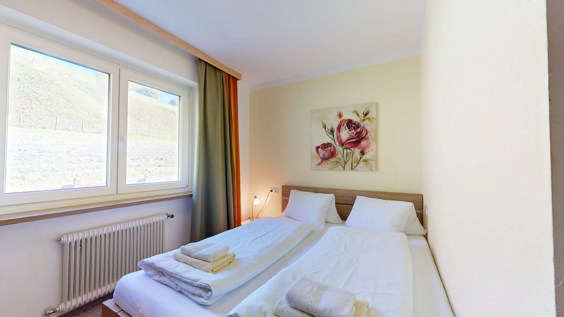 Familienzimmer mit zwei Betten, Fenstern und einem Kunstwerk an der Wand