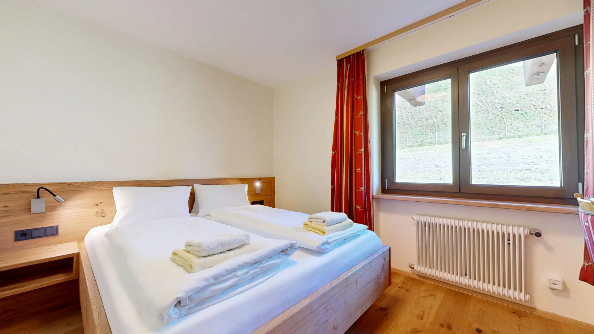 Helles Familienzimmer mit Doppelbett, Tisch und Fenstern