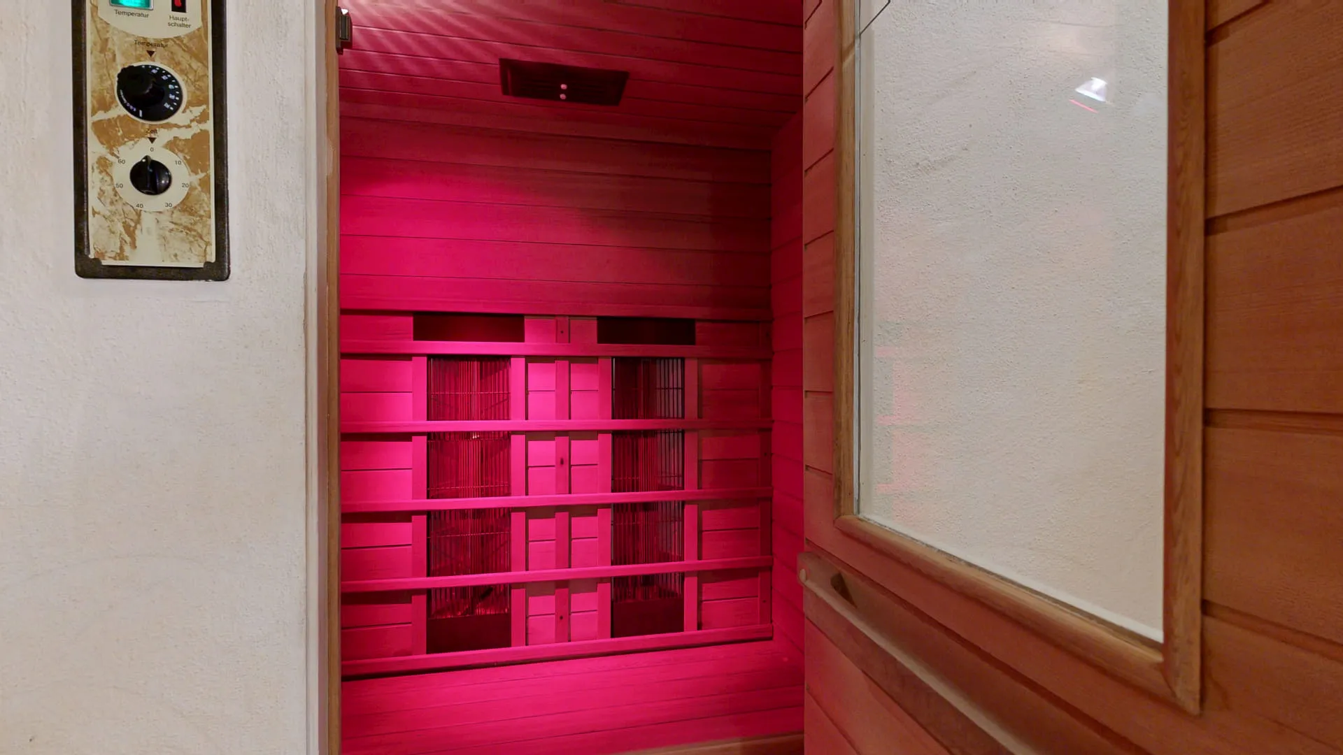 Innenansicht einer Sauna mit rosa Beleuchtung und Steuergerät