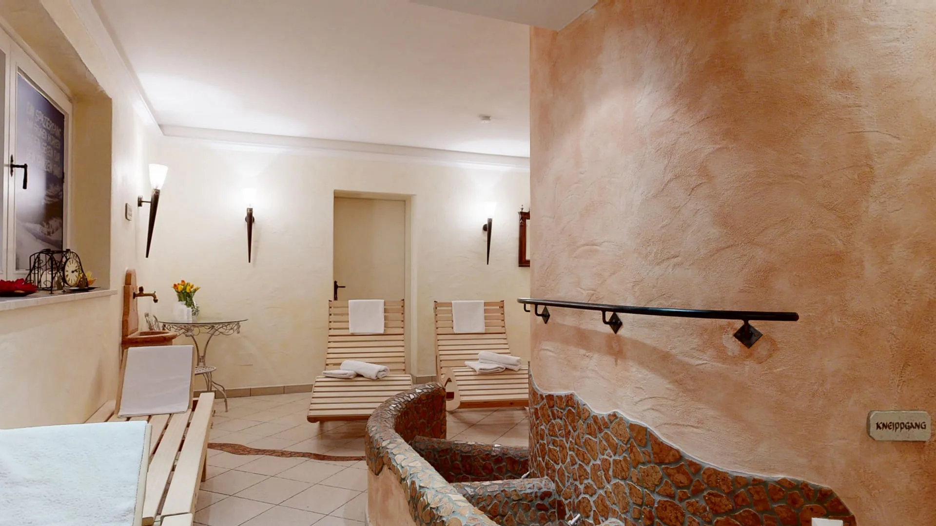 Wohlfühlraum mit Liegen, sanften Wänden und dekorativen Elementen.