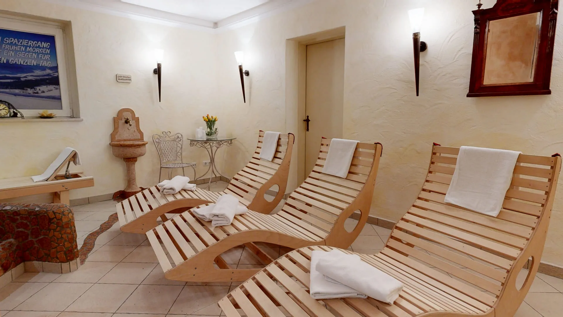 Wellnessbereich mit Holzliegen und Handtüchern, Blumendekoration, und Wänden in neutralen Farben